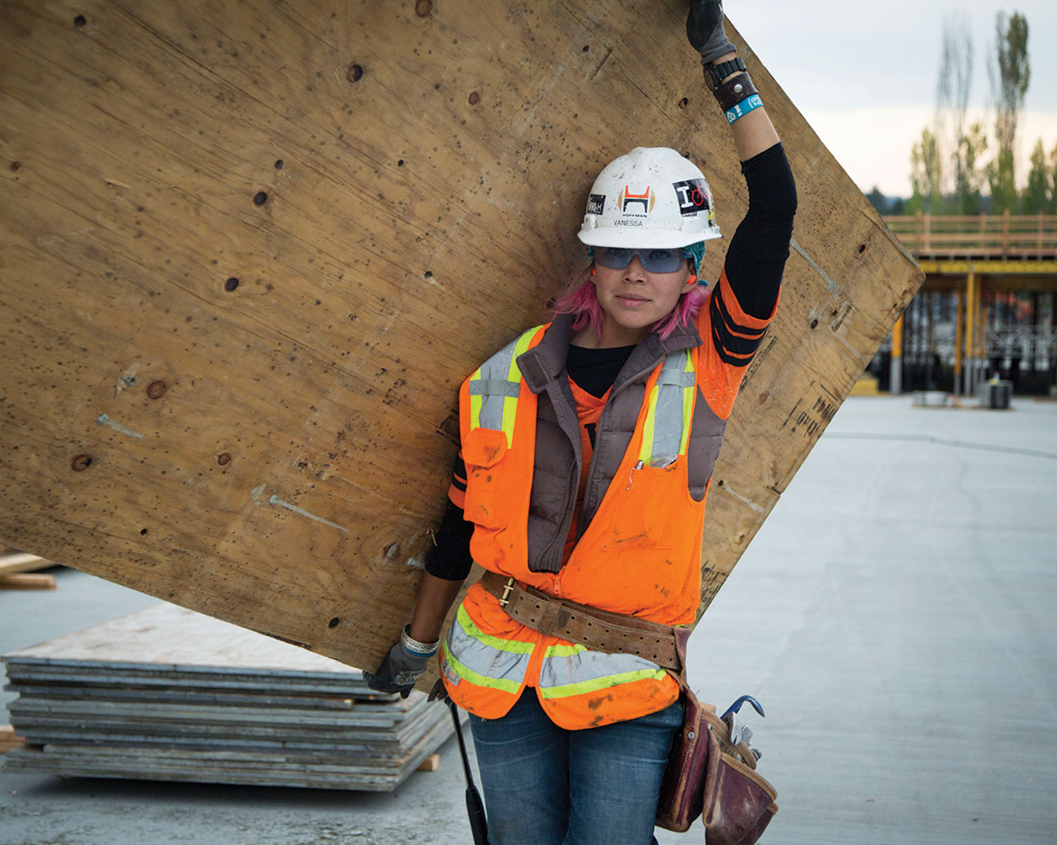 female construction worker carrying plywood