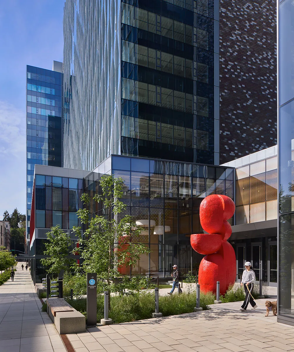 people and dog walking in front of public artwork