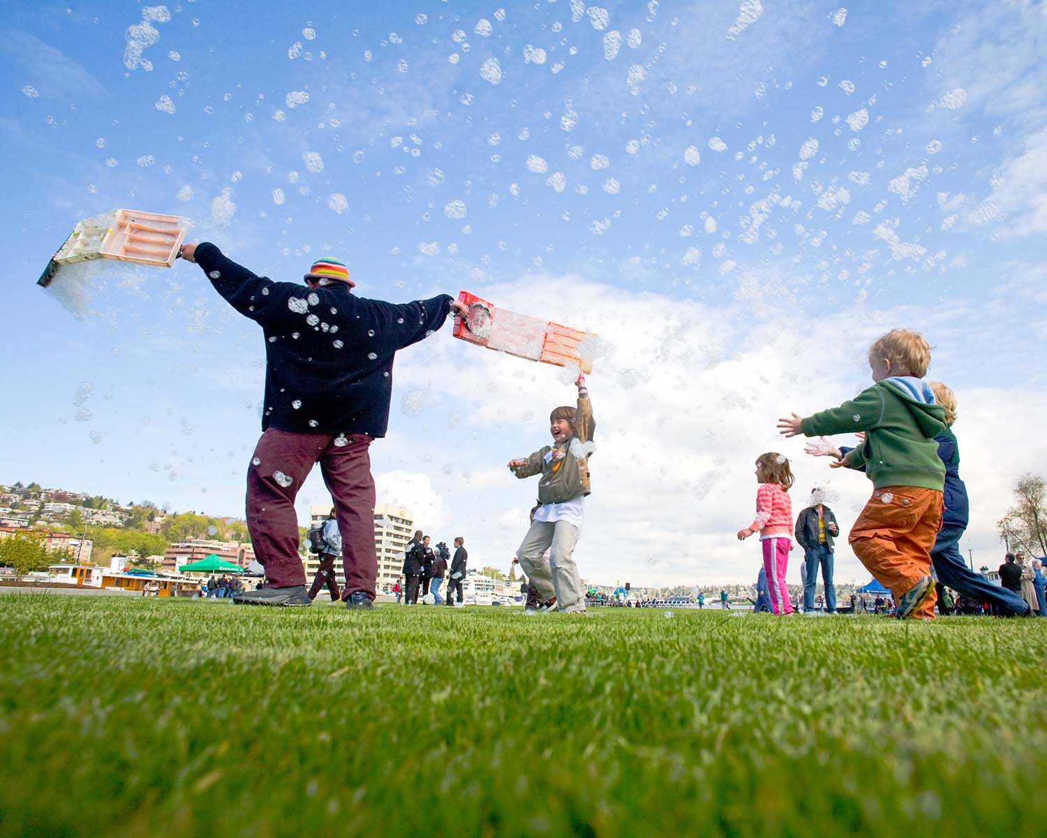 Adult and kids playing in park with bubbles